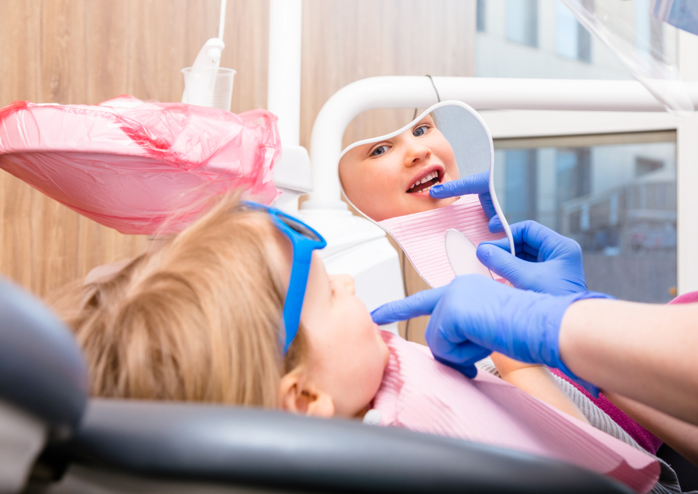 Little Girl Looking at Cured Teeth Thru the Mirror in Pediatric