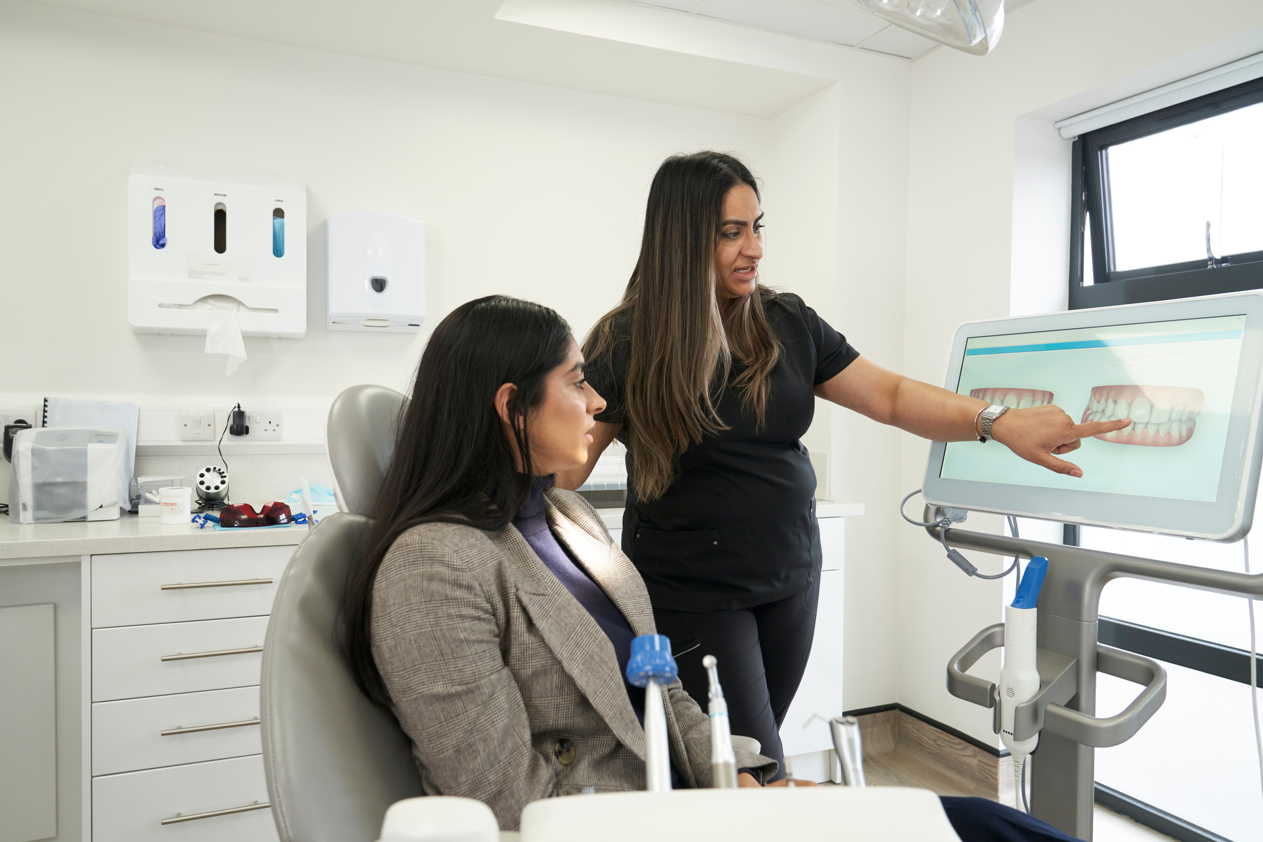 Indian dentist and patient in a modern dental surgery. The dentist talks to the patient and smiles