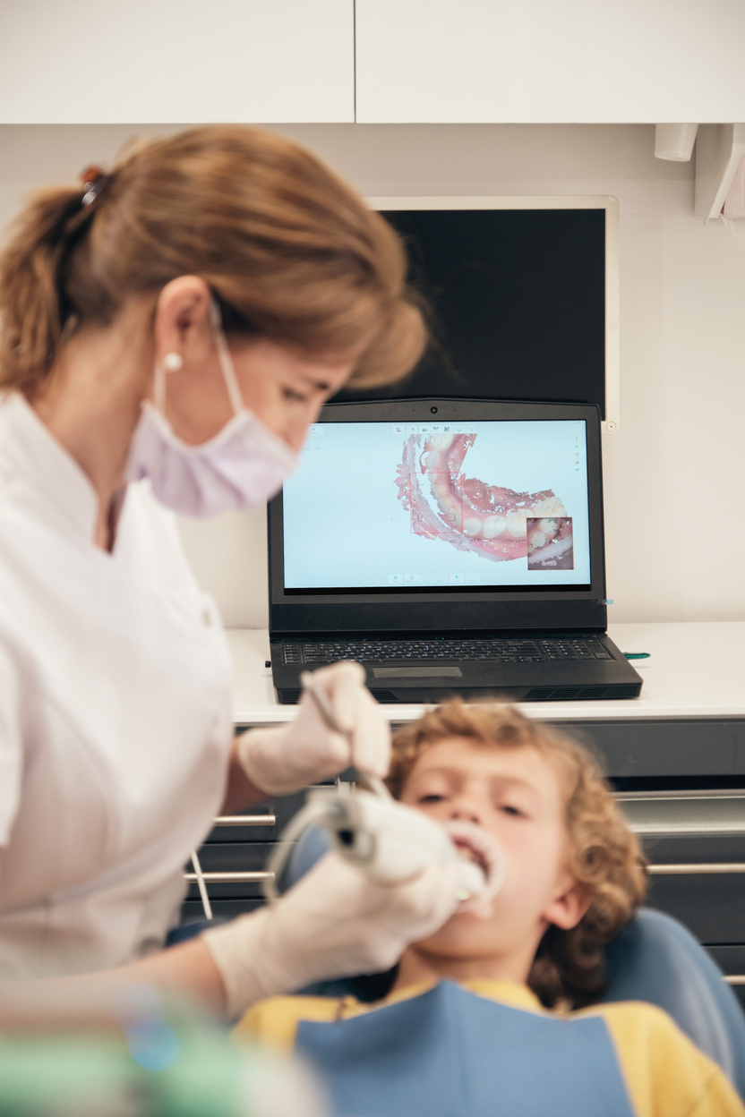 Dentist applying intraoral scanner to boy for displaying tee